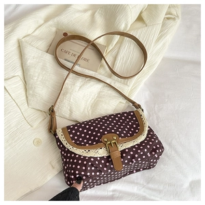 Detailed close-up of retro polka dot canvas bag featuring lace edges and bronze buckle