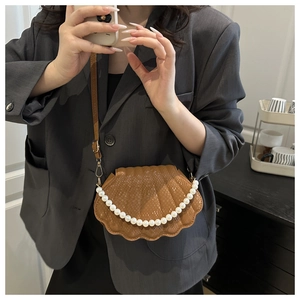Detail of a brown snakeskin pattern shell bag with pearl trim and adjustable strap