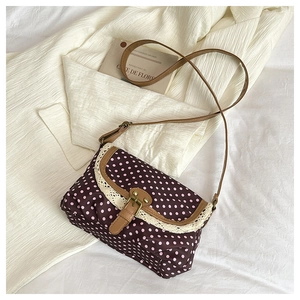 Close-up of retro canvas bag with pink polka dots, lace trim, and leather strap detail