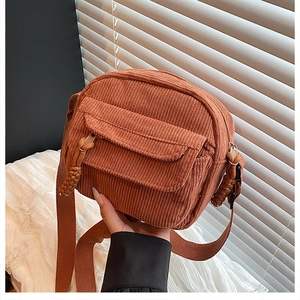 Détail du sac bandoulière en velours côtelé orange avec poche avant et tirette tressée