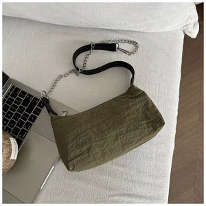 Detail of olive green pleated nylon bag with metal chain strap on textured fabric