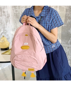 Detail of pink cartoon duck backpack featuring decorative yellow beak and feet accents