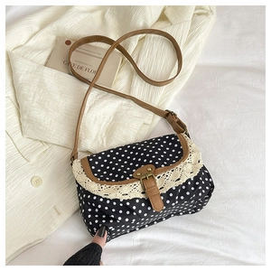 Detailed shot of retro polka dot canvas bag with lace trim and brown leather strap
