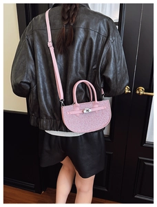 Close-up of pink glitter half-moon crossbody bag with silver buckle on a female model