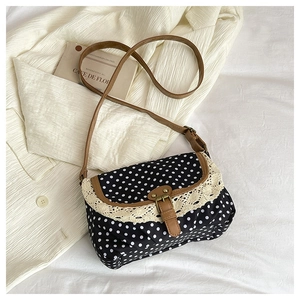 Detail of vintage polka dot canvas bag with lace trim and brown leather strap buckle