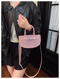 Detail of a pink sequin saddle bag with silver twist lock and chic metal hardware