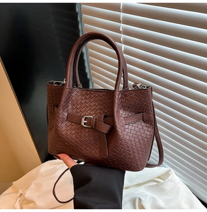 Dettaglio della trama intrecciata di una borsa in pelle marrone con fibbia e tracolla sottile