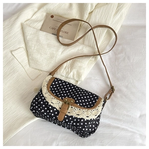 Close-up of black polka dot canvas bag featuring lace edges and brown leather strap