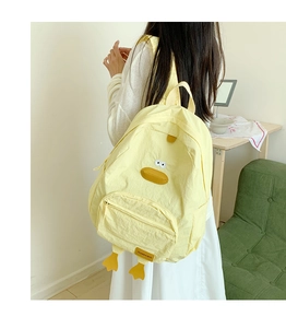 Detailed back view of a cute yellow cartoon duck backpack worn in a cozy home setting