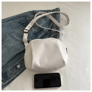 Detailed view of white nylon shell bag next to a phone showing compact daily size