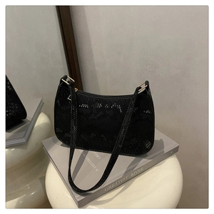 Detail of black faux snake skin texture and gold metal buckle on a chic shoulder bag