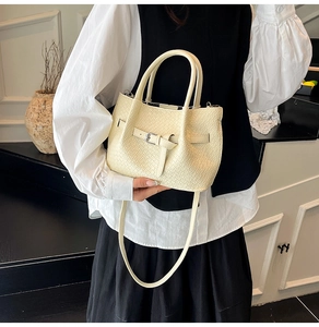 Détail du sac seau tressé crème avec boucle argentée et fine bandoulière pour femme