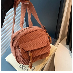 Détail de la texture du sac en velours côtelé marron avec fermeture éclair tressée