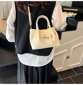 Détail du sac panier tressé blanc crème porté en bandoulière par le mannequin