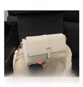 Dettaglio borsa quadrata bianco avorio con fibbia a V dorata in confezione regalo