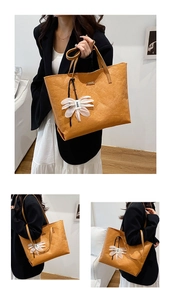 Macro shot of retro orange leather tote bag texture and white floral pendant detail