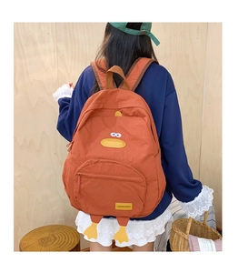 Rear view of an orange cartoon duck backpack with plush details on a female model