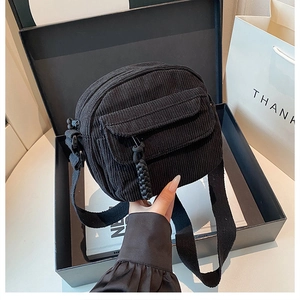 Detailed view of black corduroy crossbody bag texture in premium gift box packaging