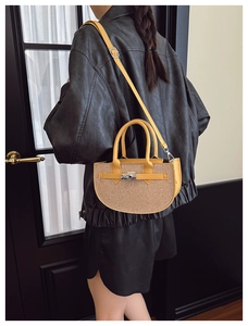 Detail of woven saddle bag featuring yellow leather trim and silver metal rotary buckle