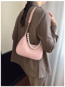 Detail of light pink hobo bag featuring pearl chain strap and leather shoulder strap
