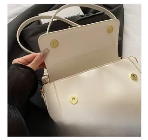 Dettaglio delle fibbie magnetiche dorate e trama della borsa a tracolla bianca chic
