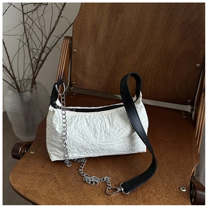 Detail of white pleated texture shoulder bag with black strap and silver metal chain