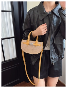 Detail of half-moon straw handbag with yellow leather trim and metal turn-lock closure