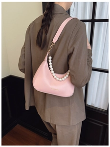 Detail of pink half-moon bag with elegant pearl chain handle and gold hardware