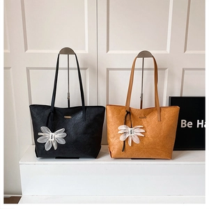 Detail der großen Shopper-Tasche mit eleganter weißer Blumen-Deko in Schwarz und Braun