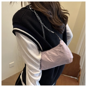 Close-up of lavender nylon shoulder bag with silver chain strap worn over a black vest