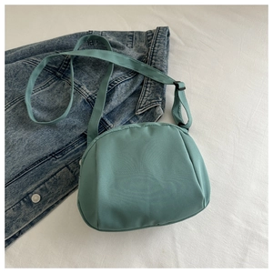 Detail view of light blue nylon shell chest bag with adjustable wide fabric strap