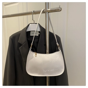 Close-up of white faux snakeskin texture and golden zipper on shoulder bag detail