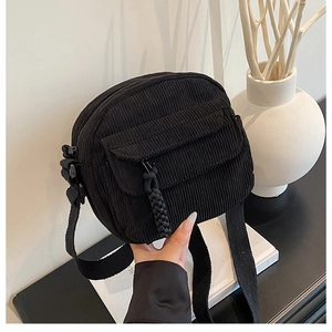 Gros plan sur un sac bandoulière en velours noir avec poche à rabat et sangle