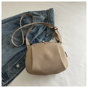 Detailed view of khaki nylon crossbody bag with adjustable strap and brand woven label