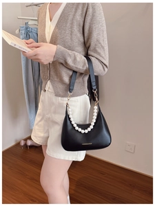 Detail of black matte PU leather underarm bag featuring decorative large pearl handle