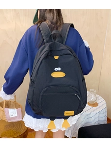 Close-up of black cartoon duck backpack with yellow feet and fashion logo patch
