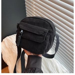 Détail du sac bandoulière en velours côtelé noir avec poche avant et tirette tressée