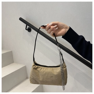 Detail of khaki nylon baguette bag with black strap and decorative silver chain
