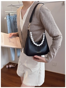 Detail view of black half-moon bag with elegant pearl chain and fashion brand logo
