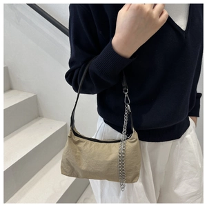 Detail of khaki nylon shoulder bag with black strap and metallic silver chain decoration