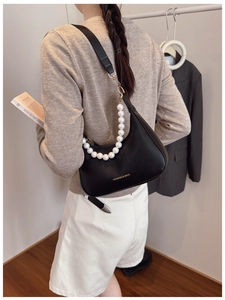 Detail of vintage black leather underarm bag featuring a white pearl decorative chain