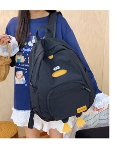 Detail view of the black cartoon duck backpack with decorative yellow feet and fashion label