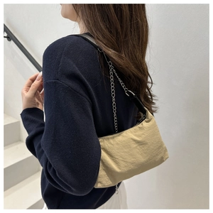 Detail of khaki baguette bag with silver chain strap on model in white setting
