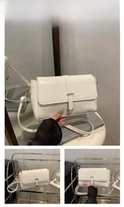 Dettaglio di una borsa a tracolla bianca minimalista con cinturino e fibbia metallica