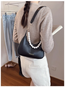 Detail of black half-moon shoulder bag with large pearl chain and gold hardware