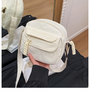 Détail du sac bandoulière en velours côtelé blanc avec poche à rabat et tirette en corde