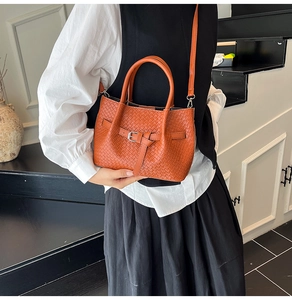 Détail de la texture tressée et de la boucle sur un sac seau luxe de couleur orange