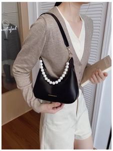 Chic black hobo bag with white pearl chain handle shown on model for size and style
