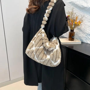 Detail of plush striped tote bag with unique furry ball beaded strap on black coat