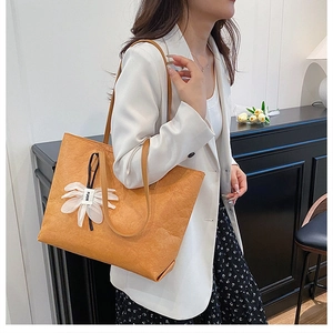 Detail of orange tote bag with crinkle texture and white flower charm on female model